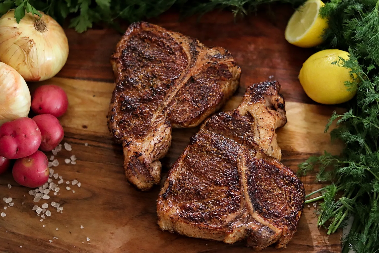 Two seared Barton Beef T-bone steaks with mushrooms, onions and fresh herbs